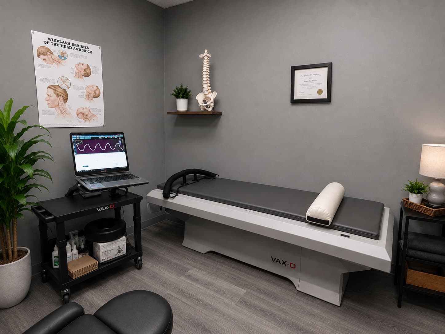 A VAX-D spinal decompression table with its computer-guided cart and monitor in a treatment room at Dixon Chiropractic and Spine Clinic in Etobicoke.